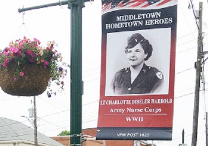 Retired Navy Captain Donald Reid stands next to a banner on South Union Street honoring an Army nurse from World War II.
